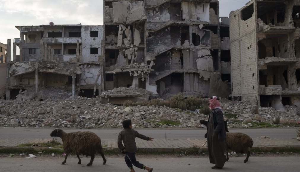 Un enfant court après les moutons en passant devant des bâtiments détruits pendant la guerre civile dans le quartier de Khalidiya à Homs, en Syrie, mercredi 1er janvier 2025. / Keystone